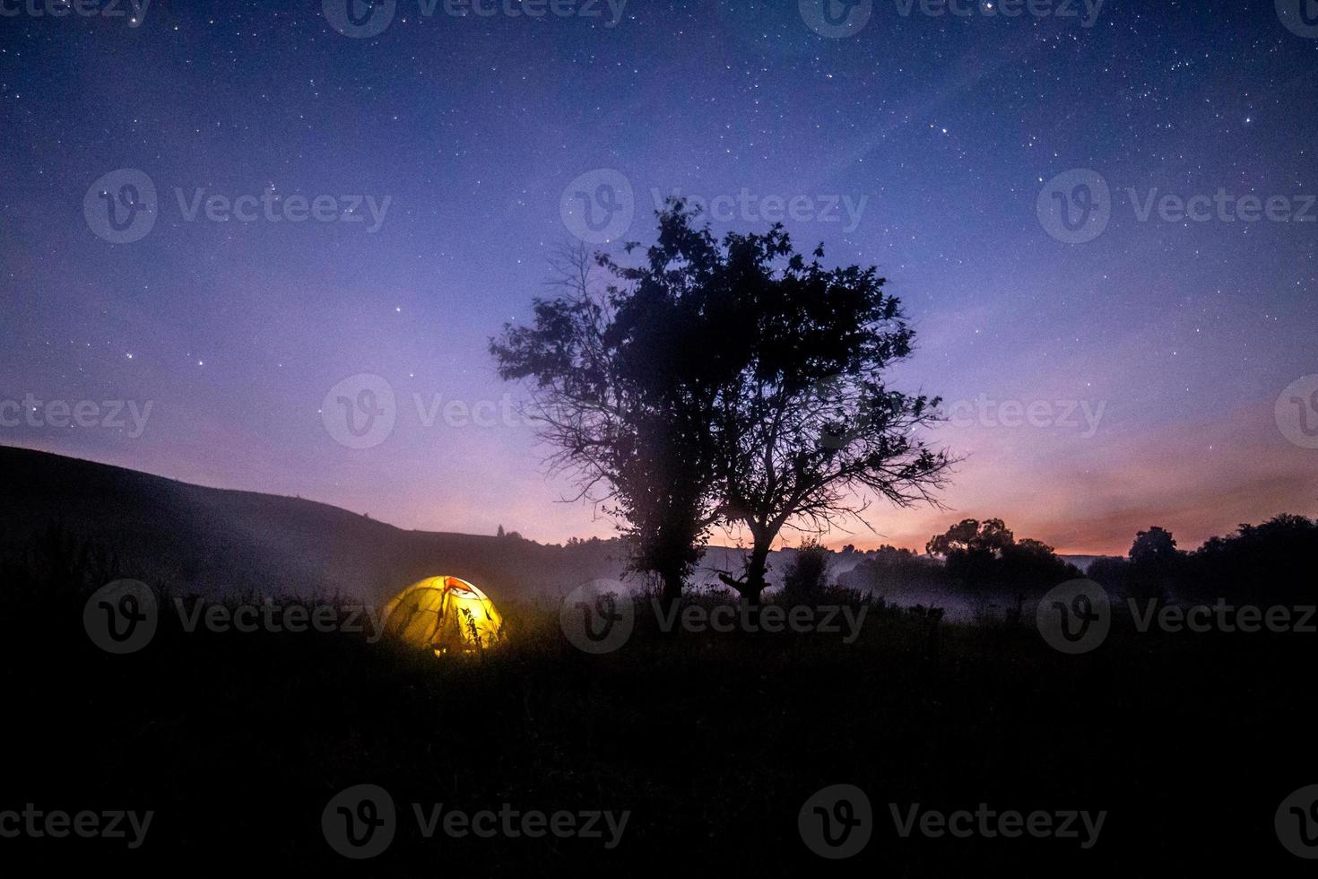 giallo tenda sotto albero a estate stellato notte con nebbia foto