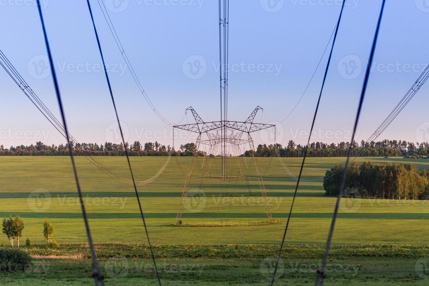 enorme energia linea torri su campo a estate sera foto