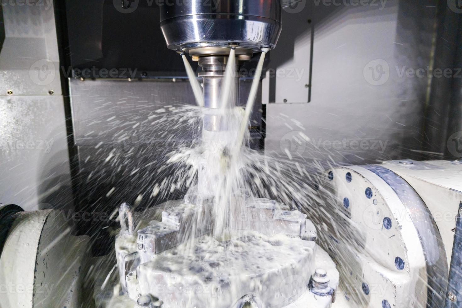 un' processi di industriale bagnato fresatura nel 5 assi cnc macchina con refrigerante flusso sotto pressione e movimento sfocatura di spruzzi foto