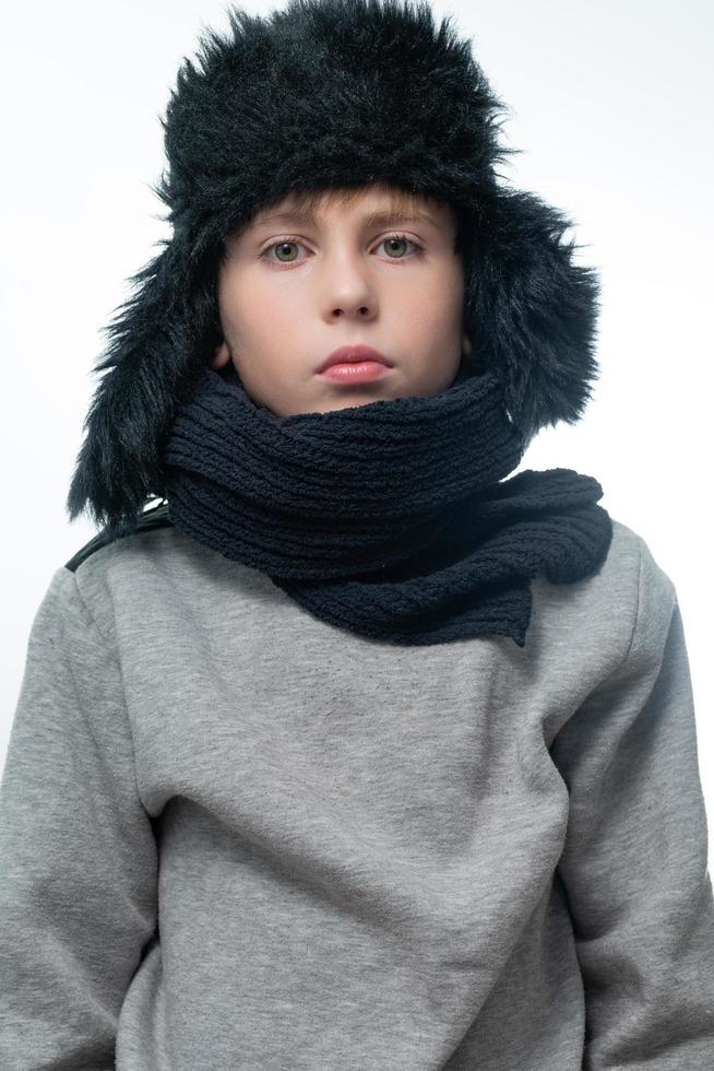 ritratto di un' bambino nel un' inverno cappello con paraorecchie e un' a maglia sciarpa su un' bianca sfondo. foto
