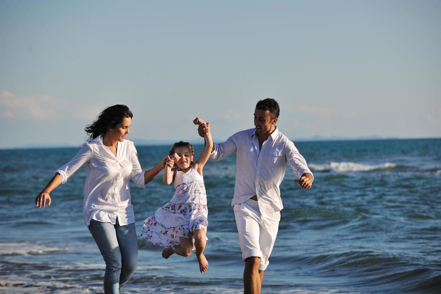 contento giovane famiglia avere divertimento su spiaggia foto