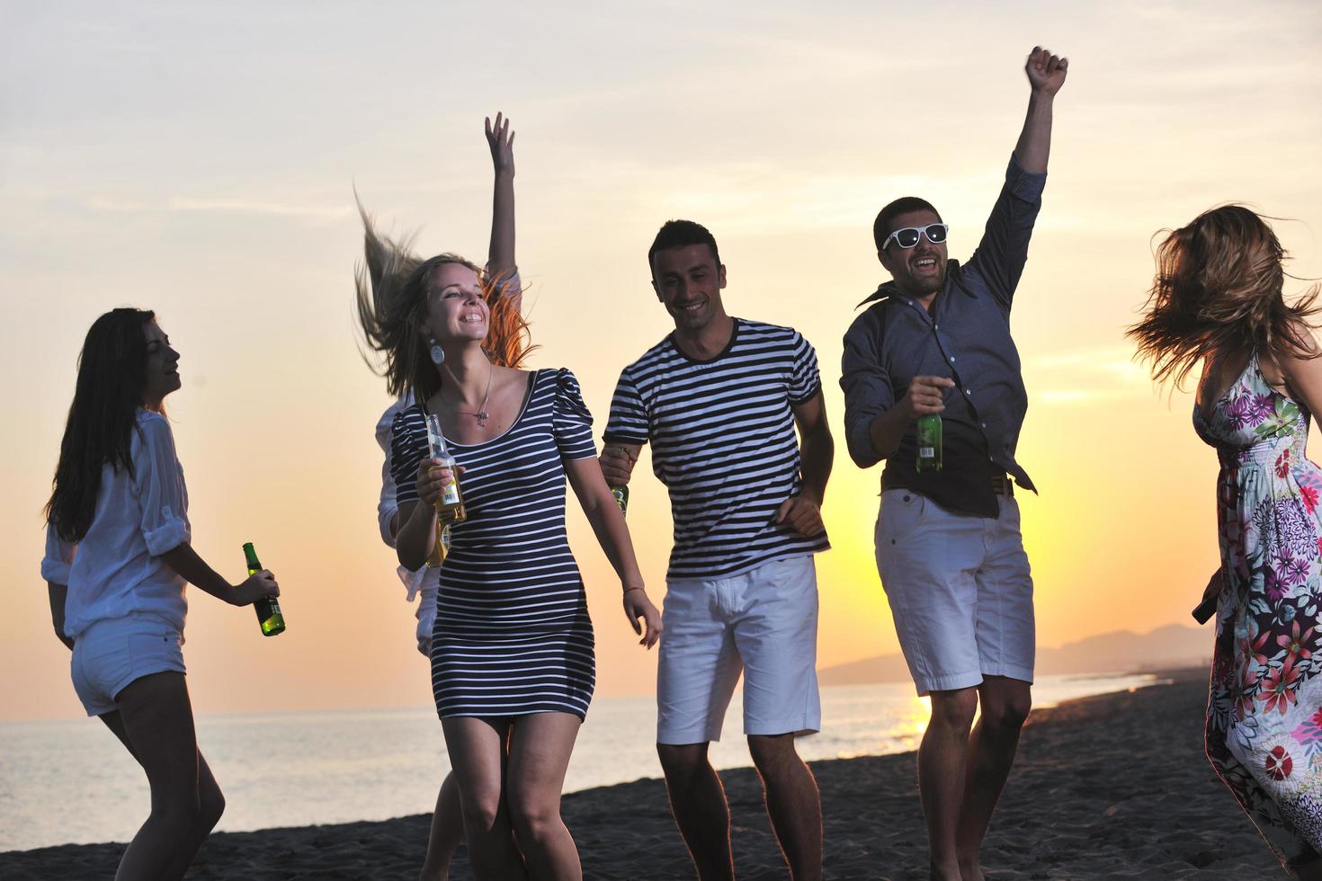 gruppo di giovane persone godere estate festa a il spiaggia foto