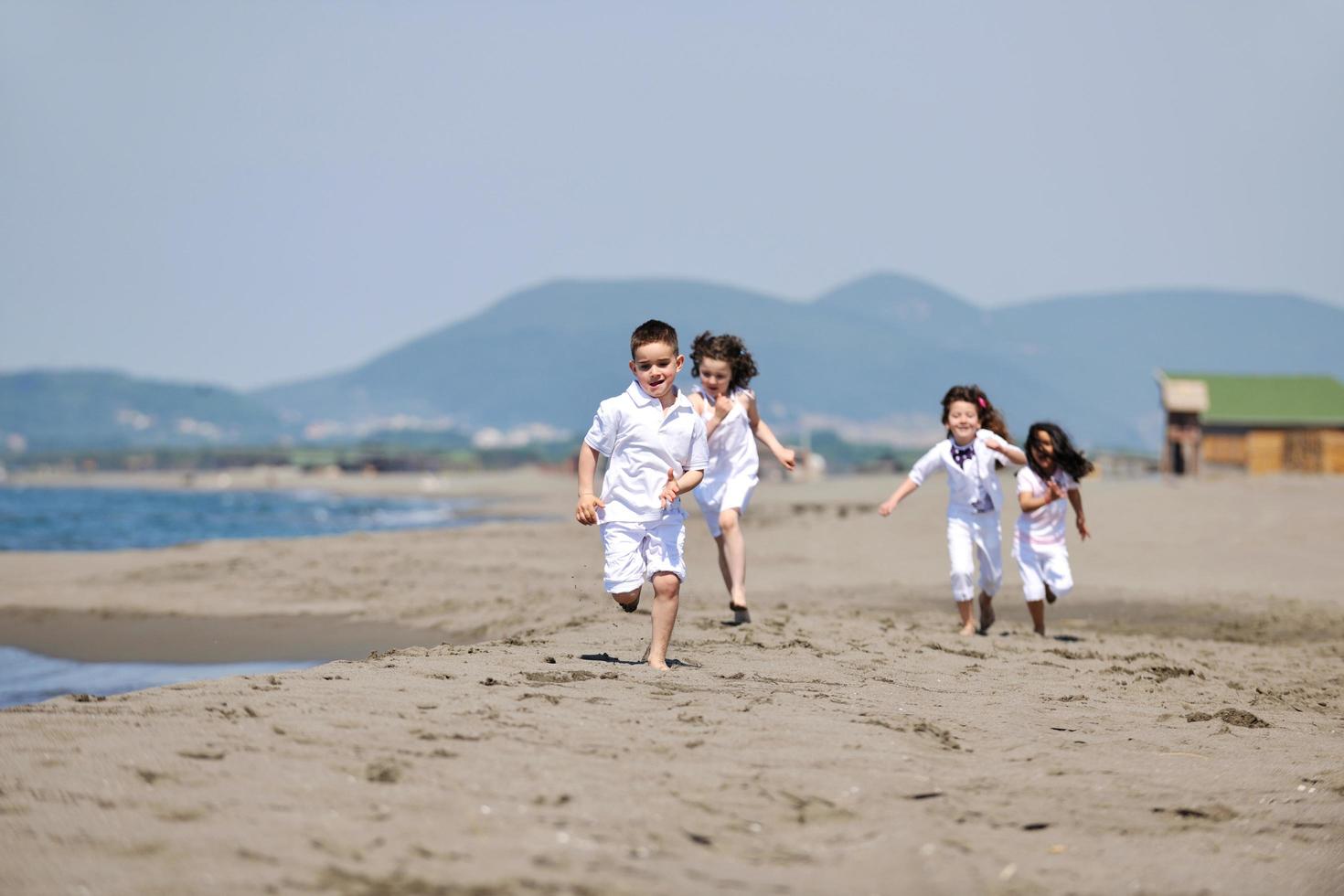 gruppo di bambini felici che giocano sulla spiaggia foto