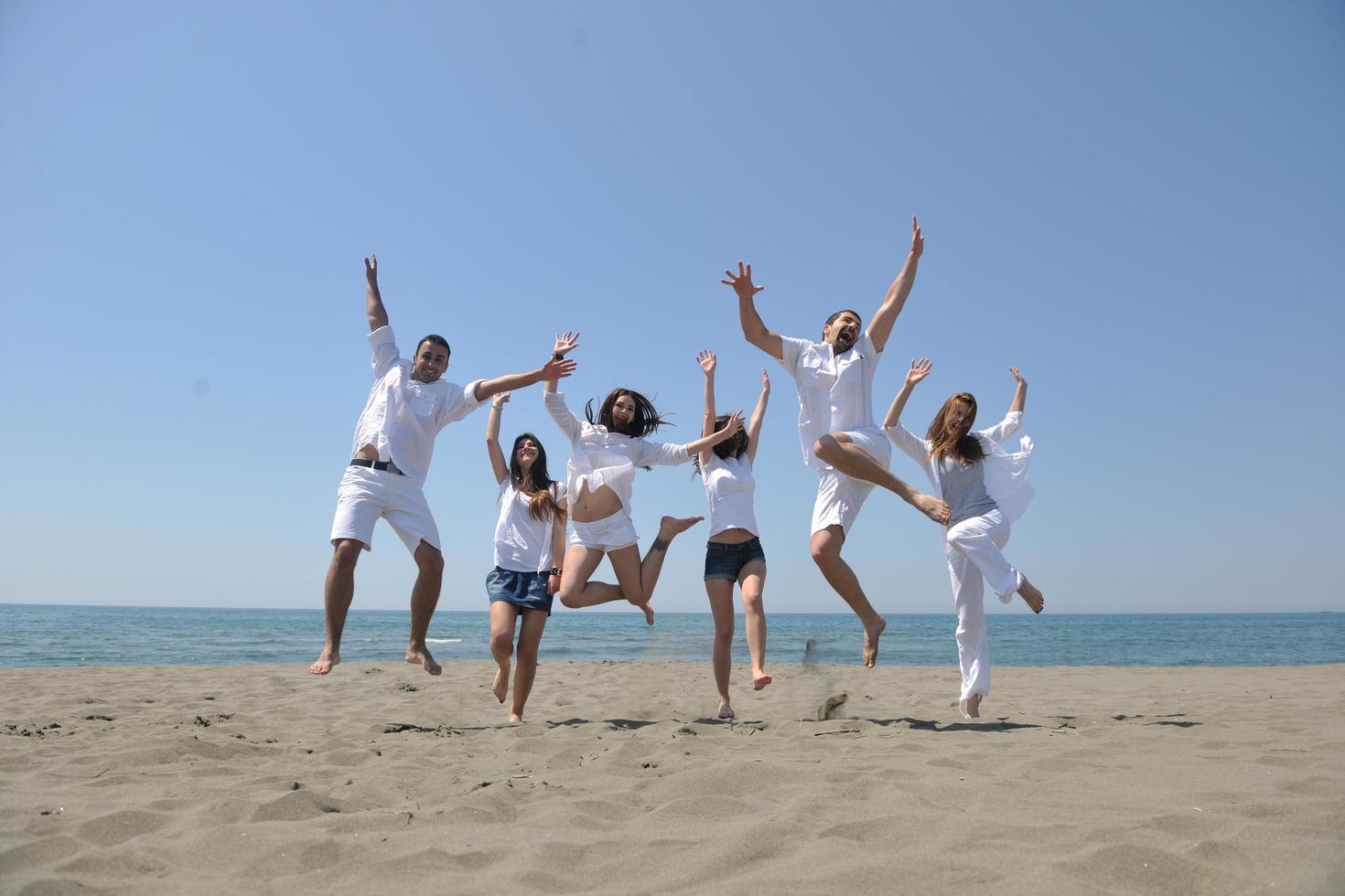 contento persone gruppo avere divertimento e in esecuzione su spiaggia foto