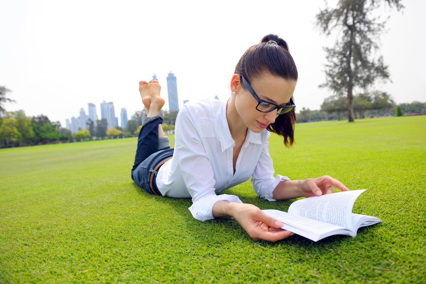 giovane donna che legge un libro nel parco foto