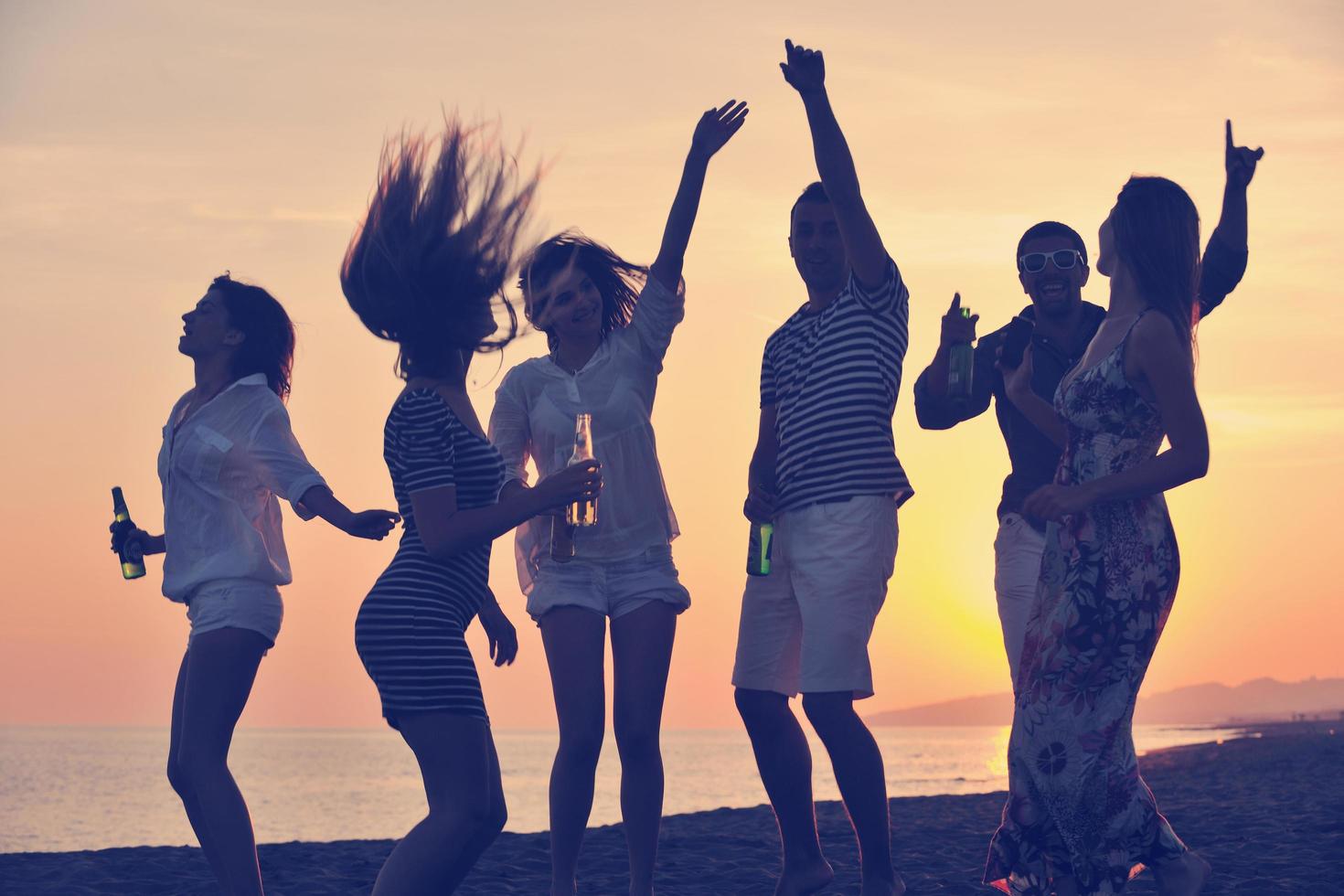 gruppo di giovane persone godere estate festa a il spiaggia foto