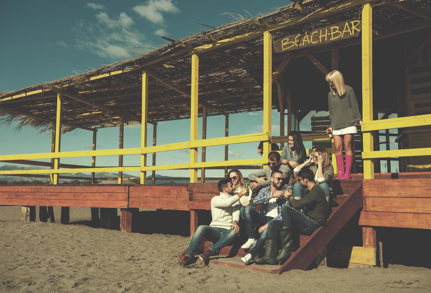 gruppo di amici avendo divertimento su autunno giorno a spiaggia foto