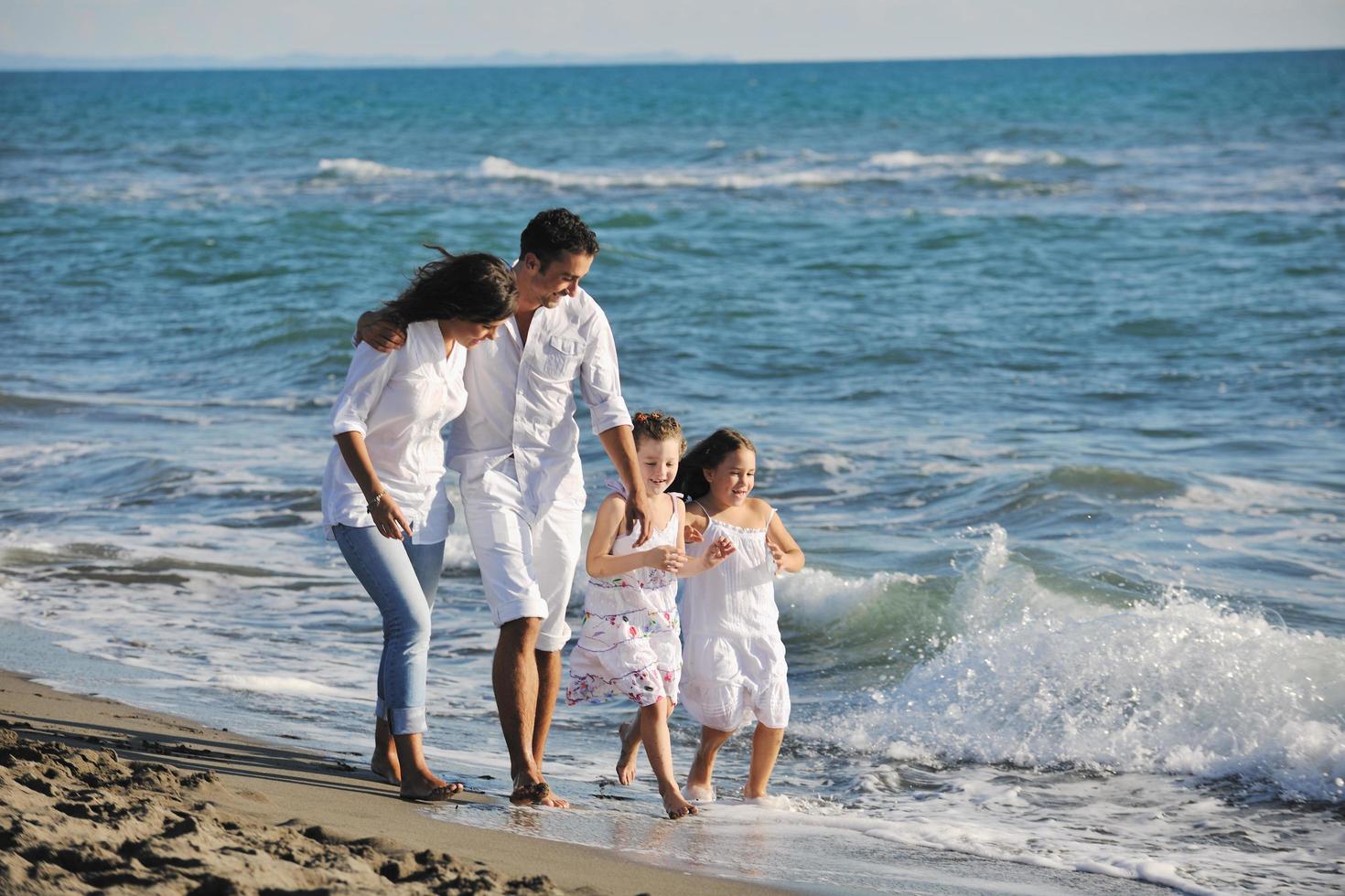 contento giovane famiglia avere divertimento su spiaggia foto