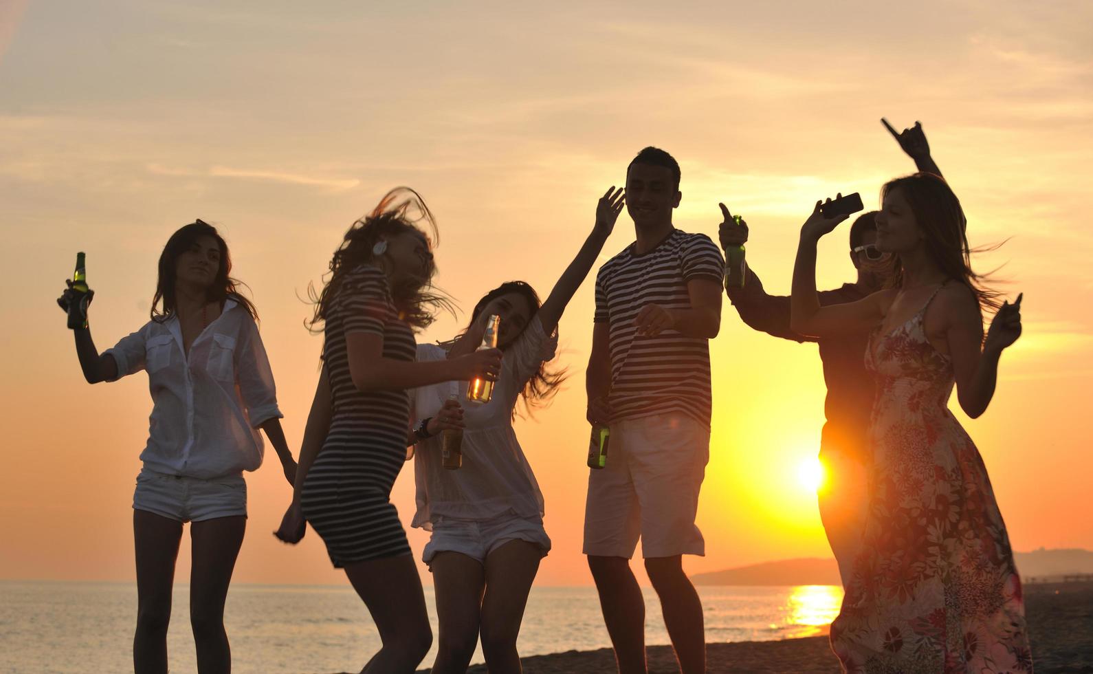 gruppo di giovane persone godere estate festa a il spiaggia foto