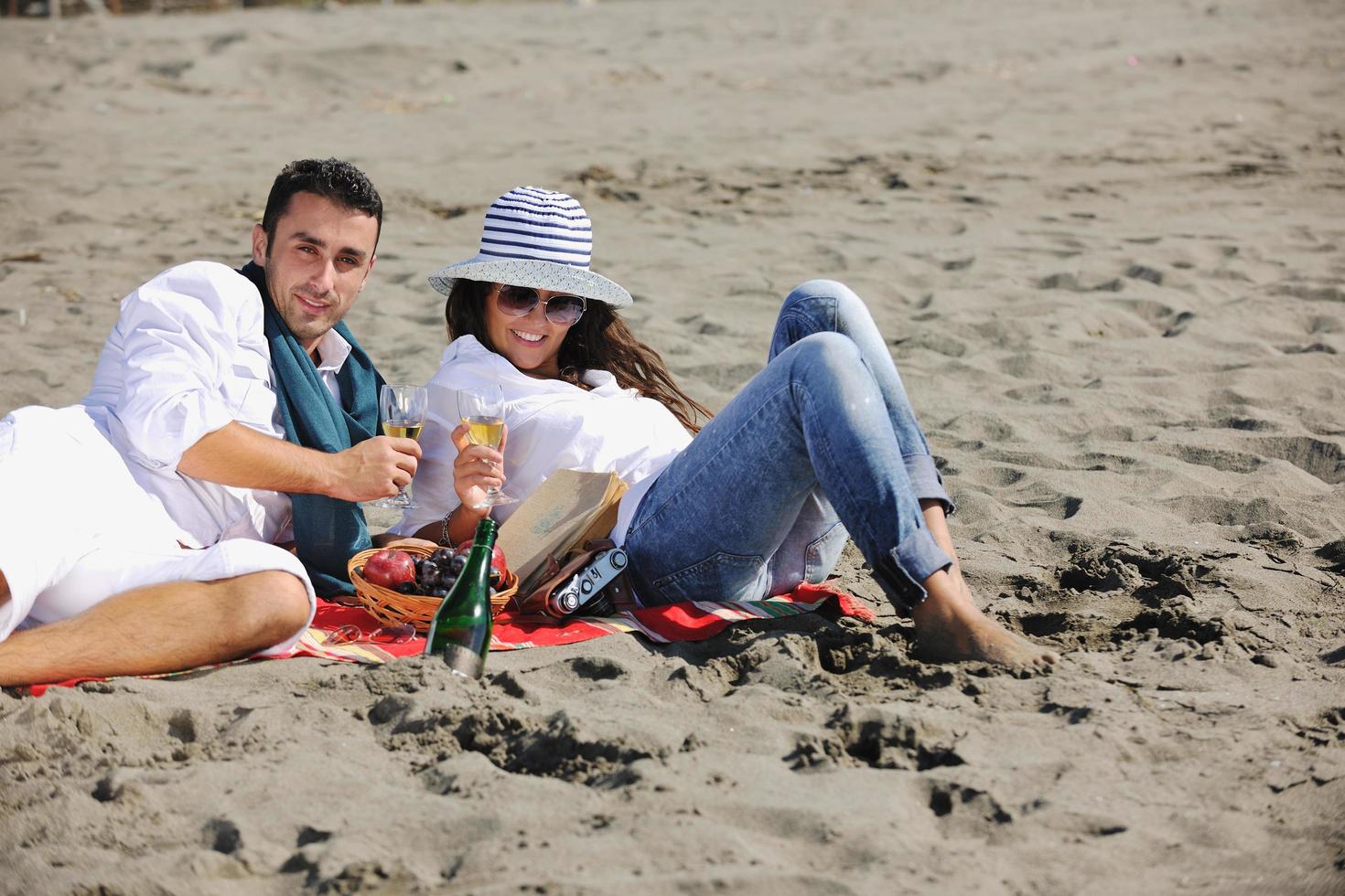 giovane coppia godendo picnic su il spiaggia foto