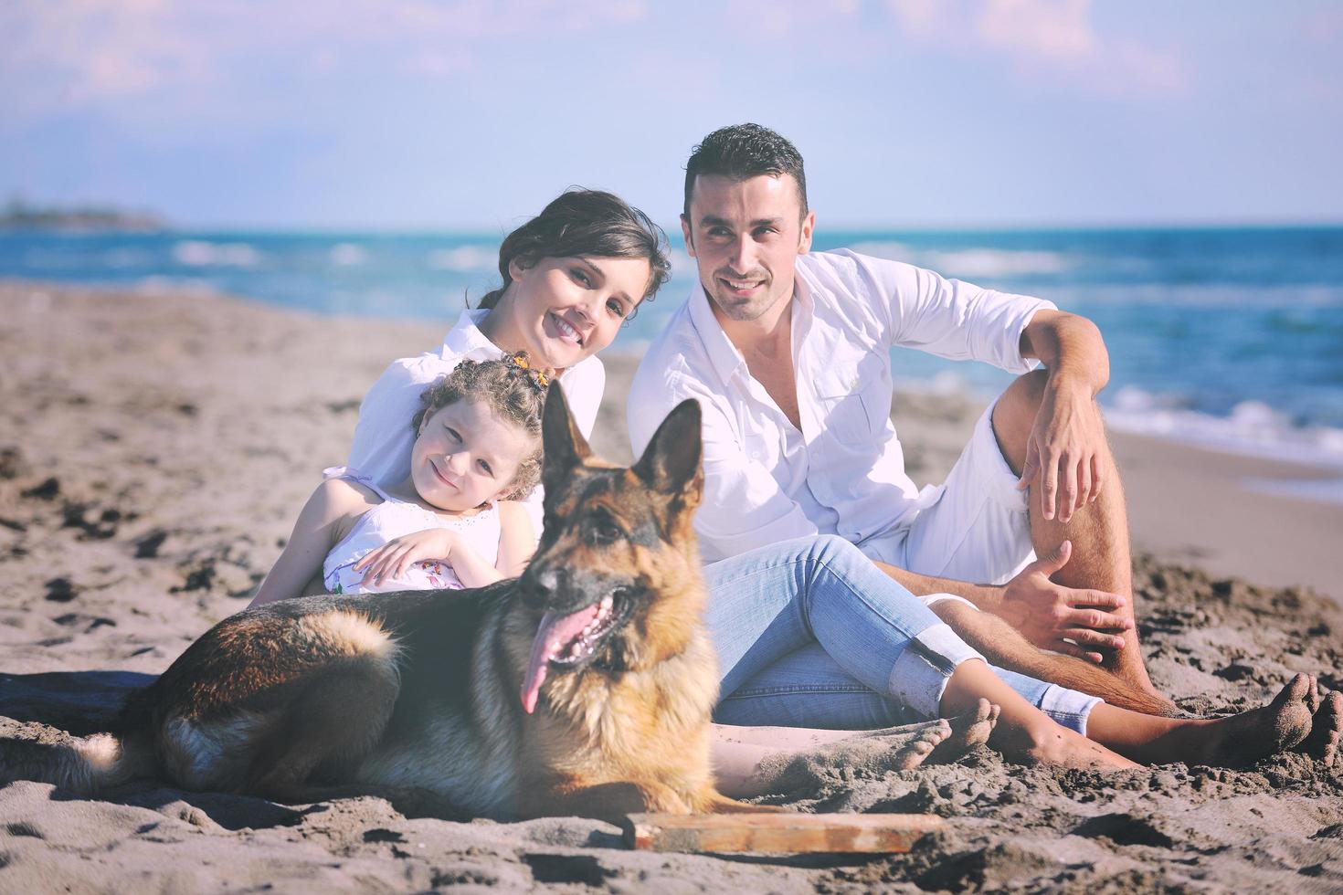 contento famiglia giocando con cane su spiaggia foto