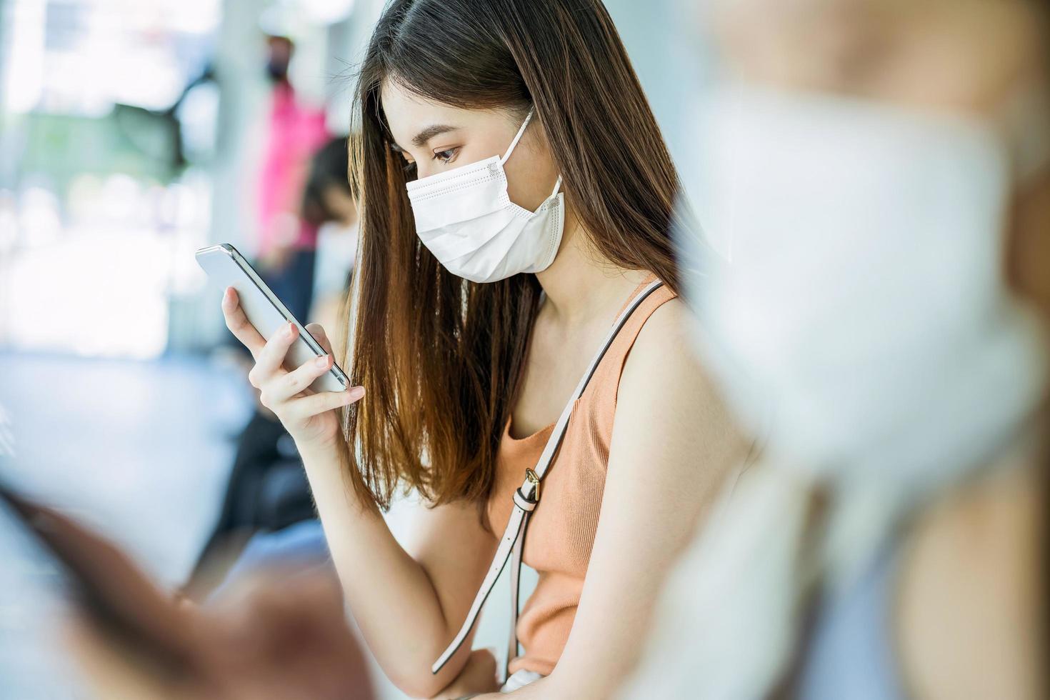 passeggero donna asiatica con maschera in attesa alla stazione foto