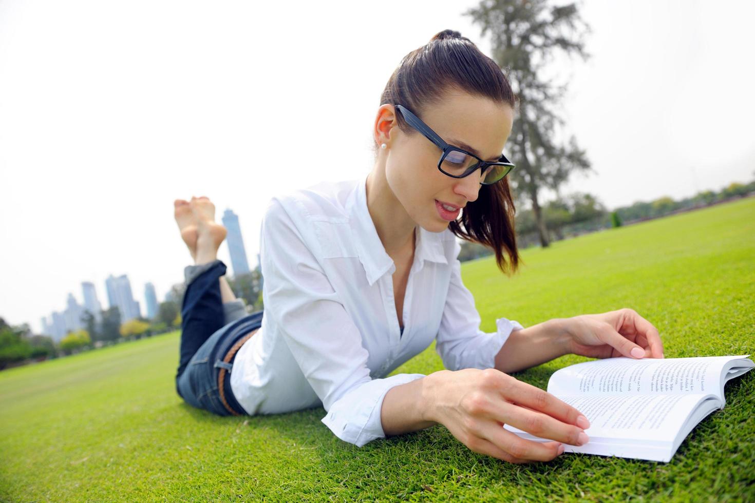 giovane donna che legge un libro nel parco foto