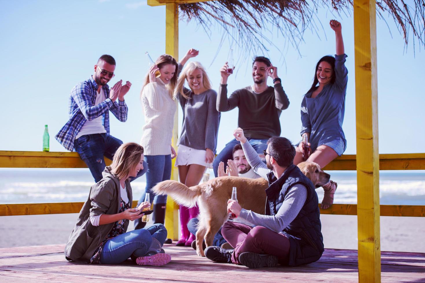 gruppo di amici avendo divertimento su autunno giorno a spiaggia foto