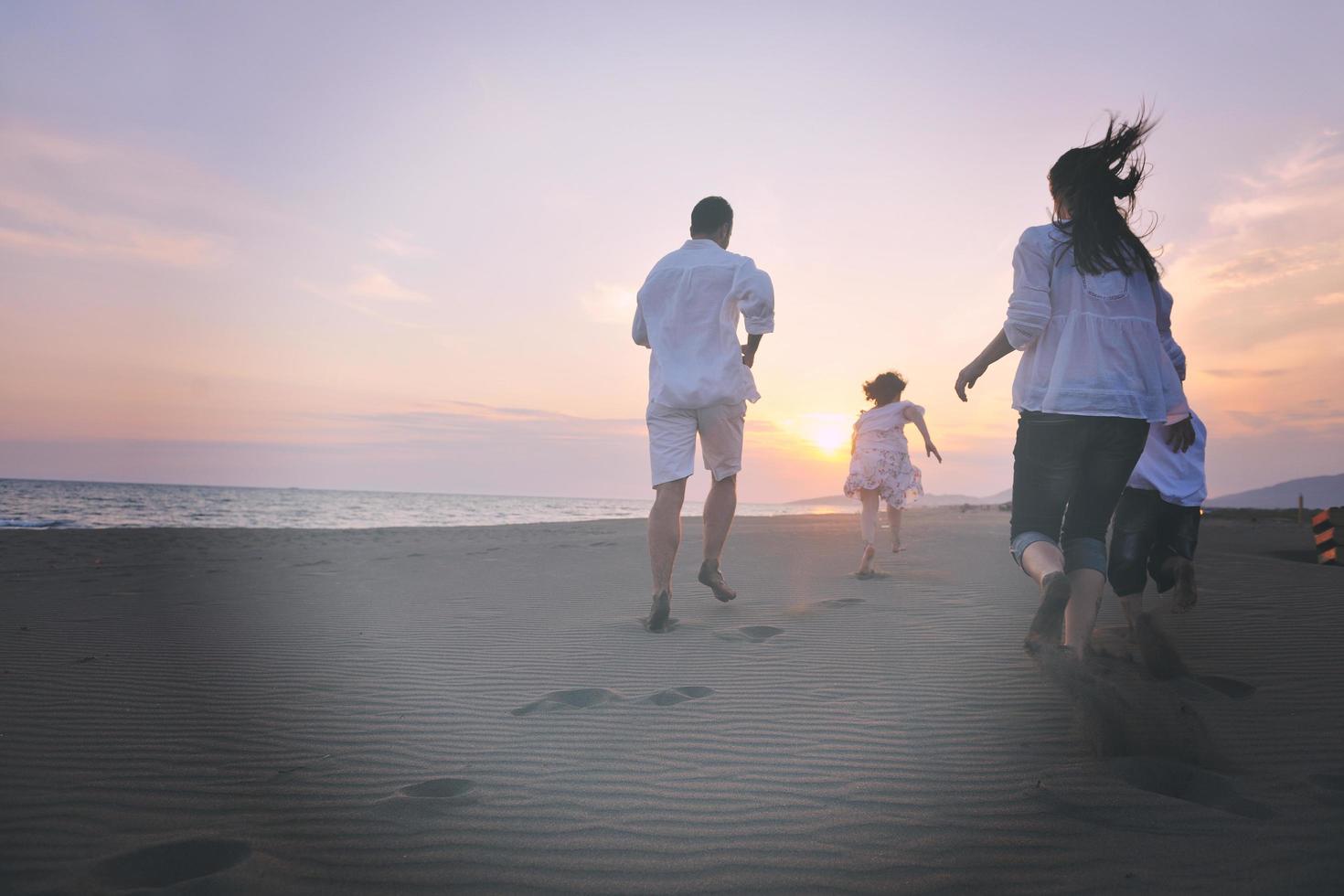 contento giovane famiglia avere divertimento su spiaggia a tramonto foto