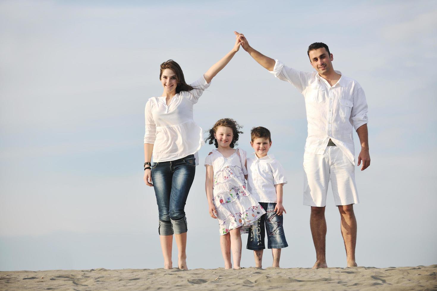 famiglia su spiaggia mostrando casa cartello foto