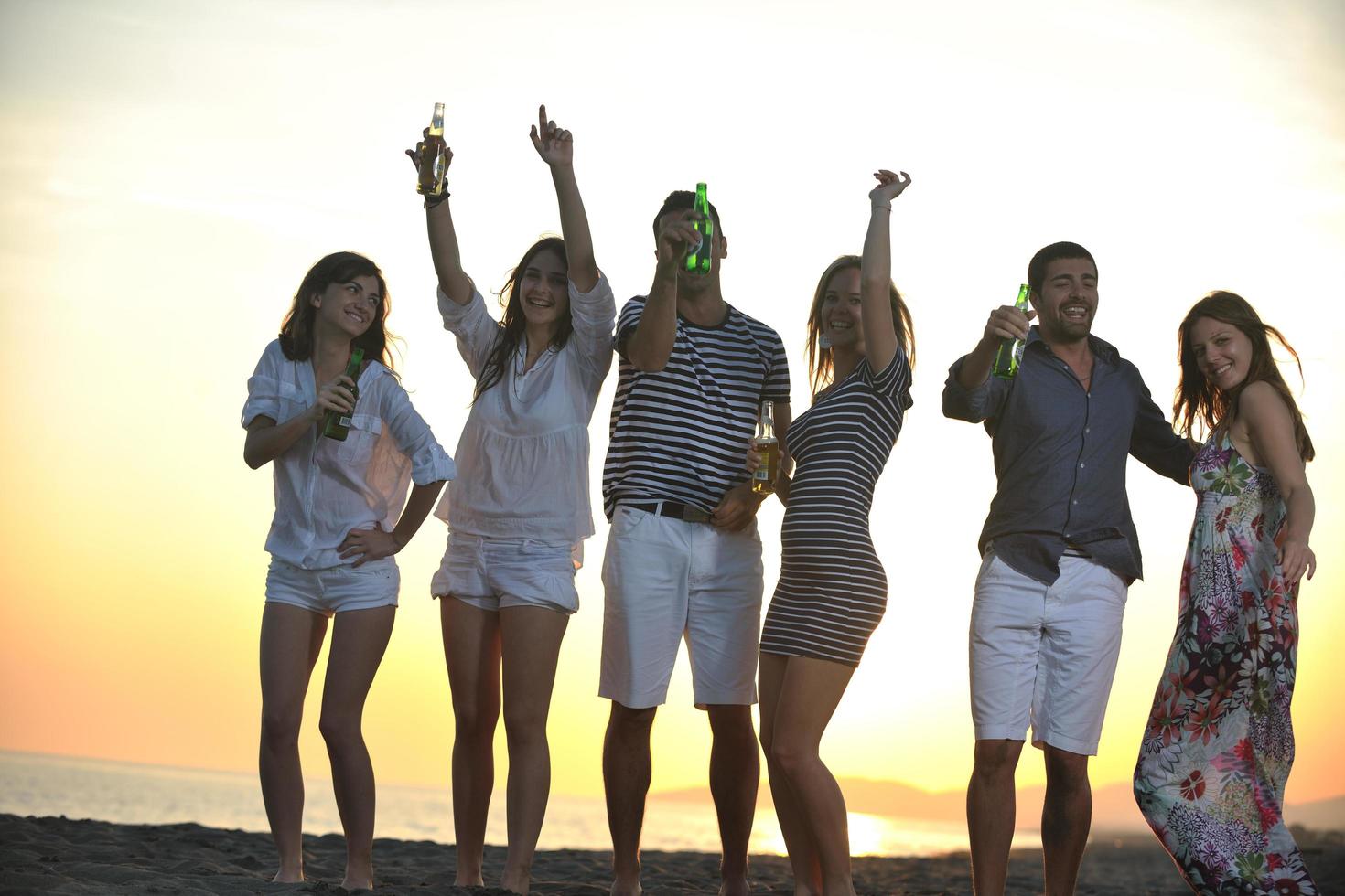 gruppo di giovane persone godere estate festa a il spiaggia foto