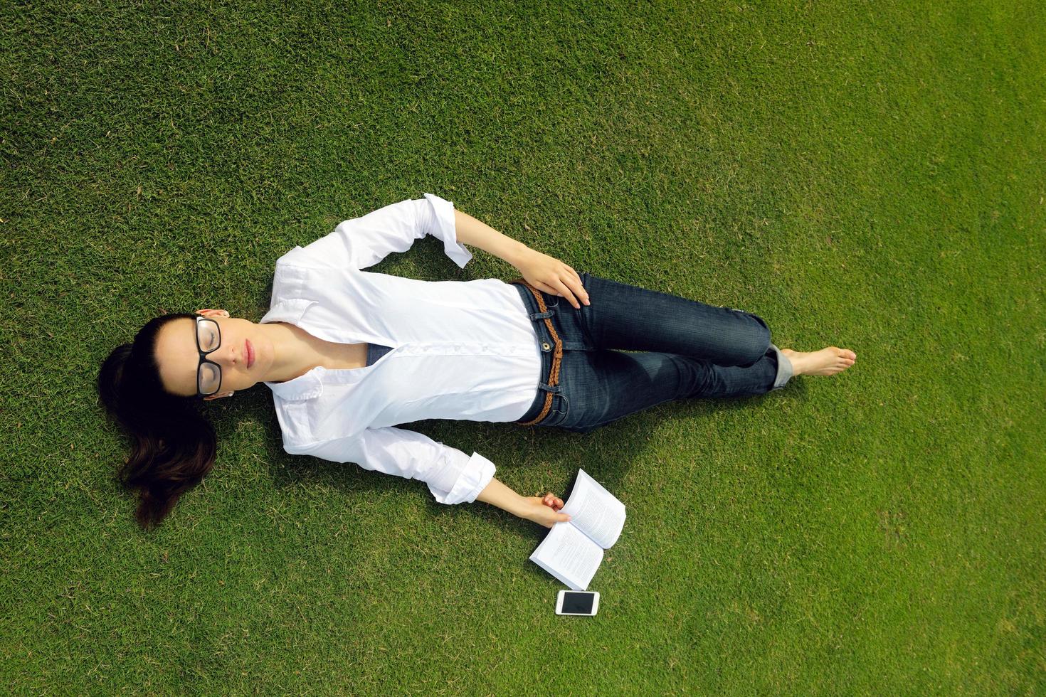 giovane donna che legge un libro nel parco foto