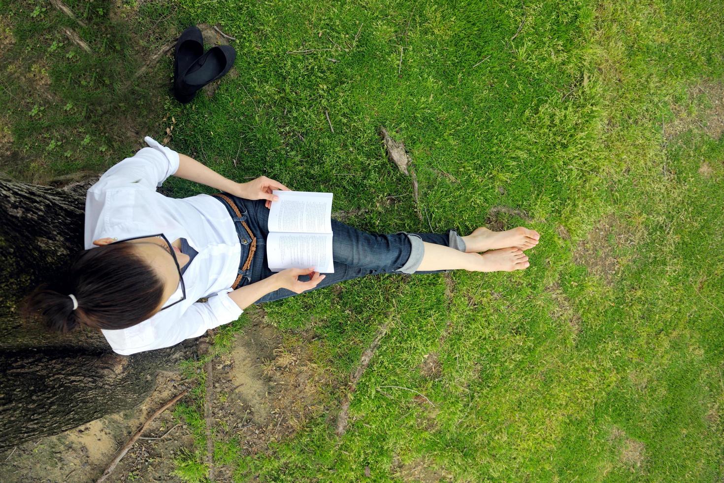 giovane donna che legge un libro nel parco foto