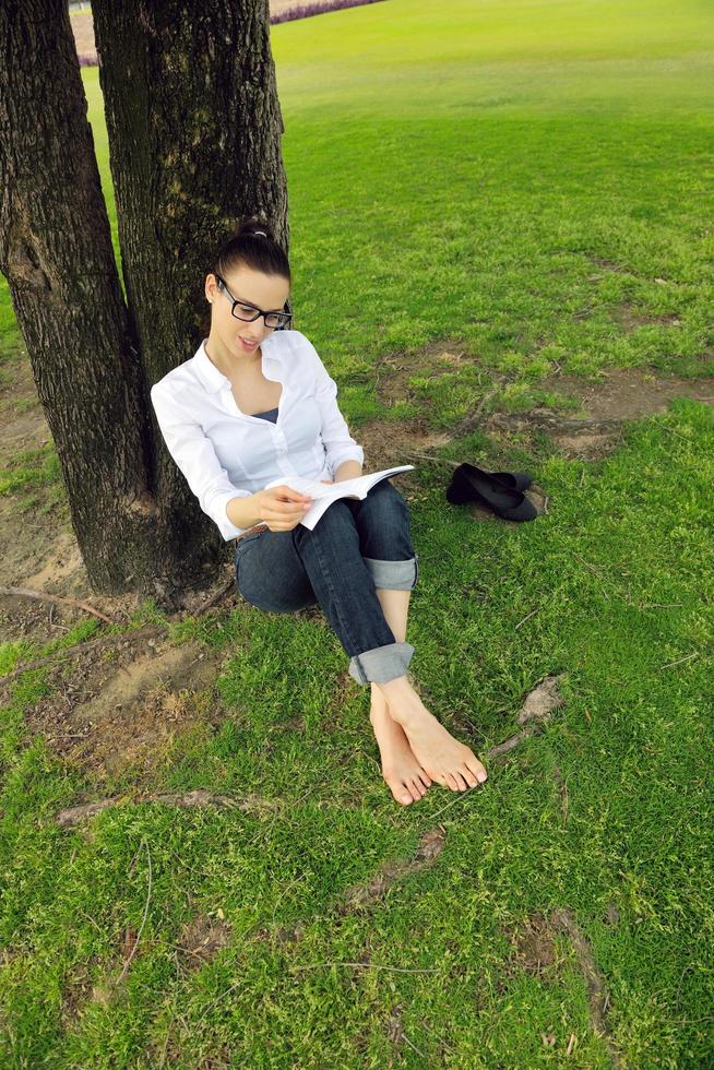 giovane donna che legge un libro nel parco foto