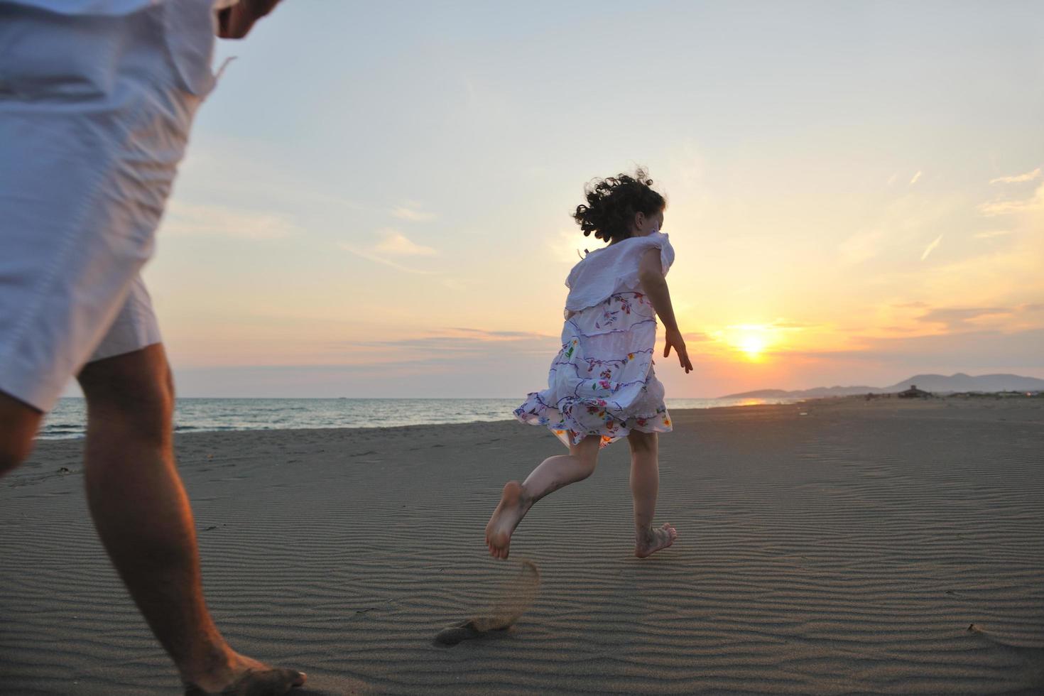 contento giovane famiglia avere divertimento su spiaggia a tramonto foto