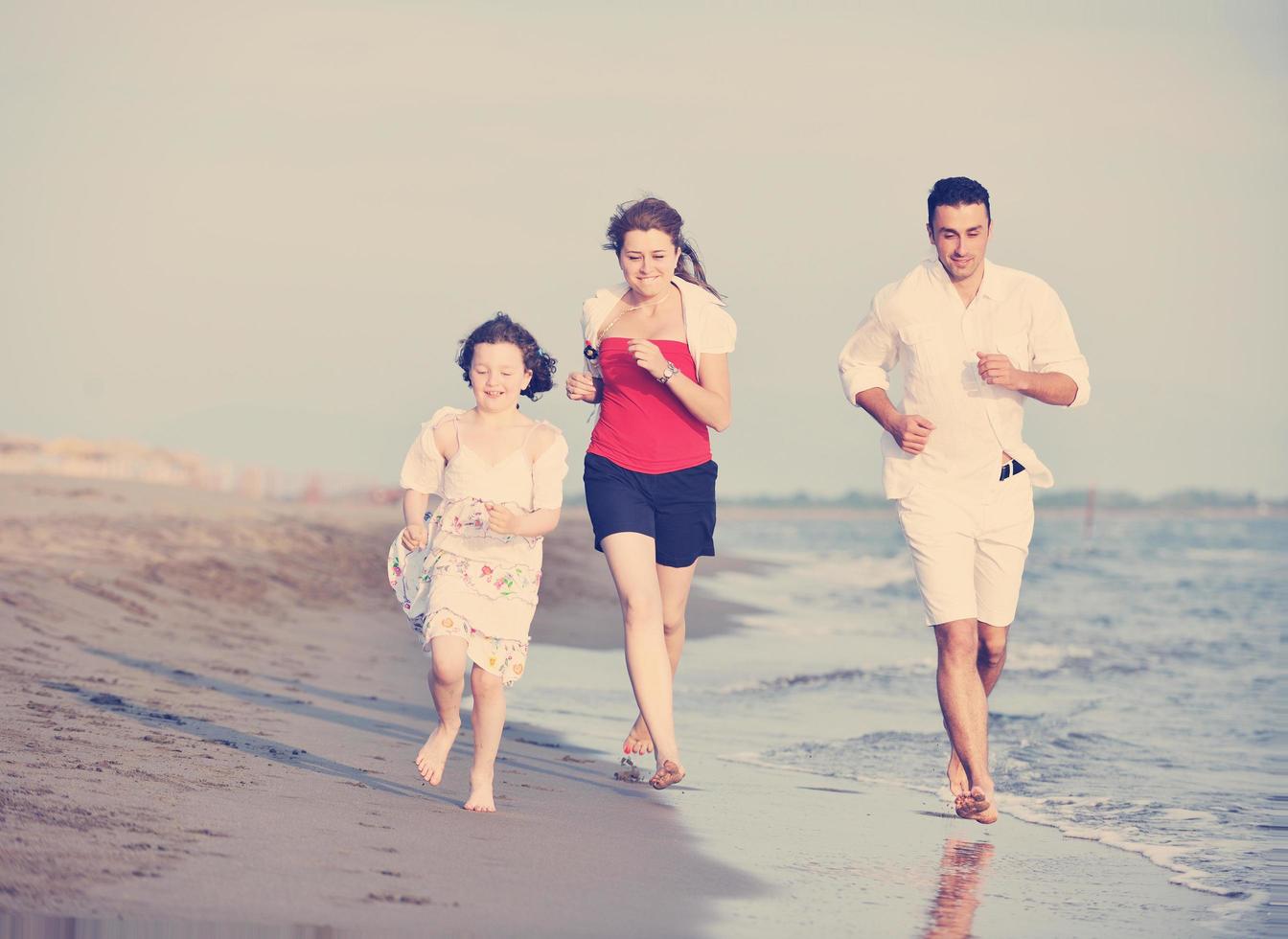 contento giovane famiglia avere divertimento su spiaggia foto