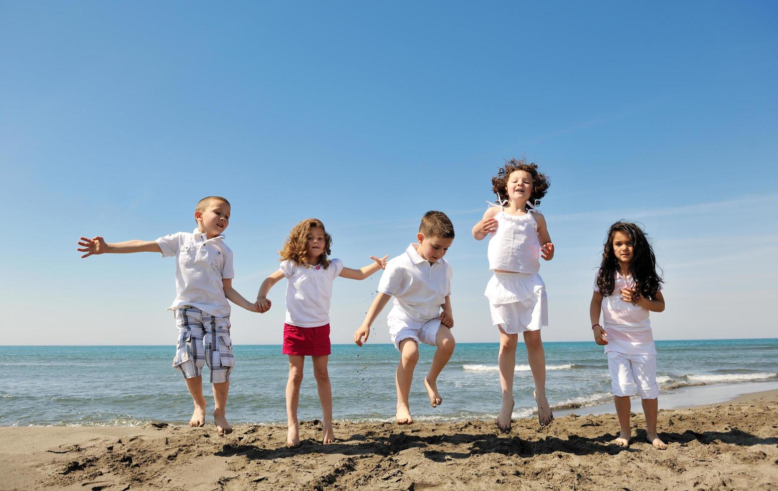 gruppo di bambini felici che giocano sulla spiaggia foto