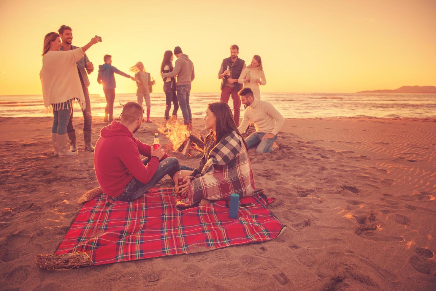 coppia godendo con amici a tramonto su il spiaggia foto