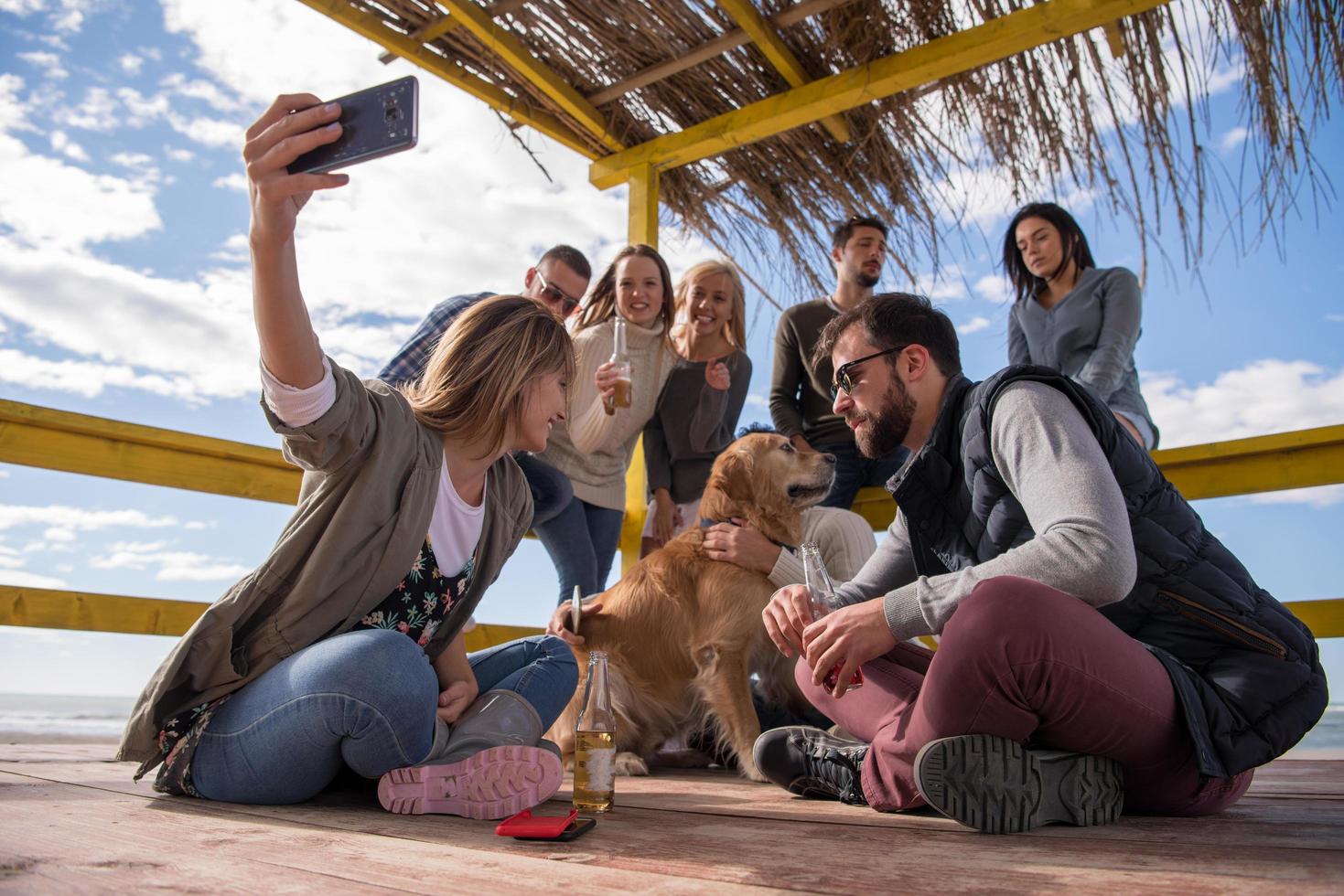 gruppo di amici avendo divertimento su autunno giorno a spiaggia foto