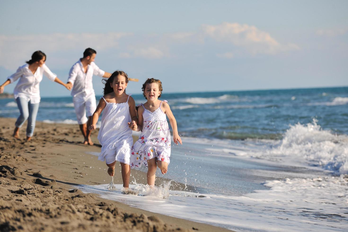 contento famiglia giocando con cane su spiaggia foto