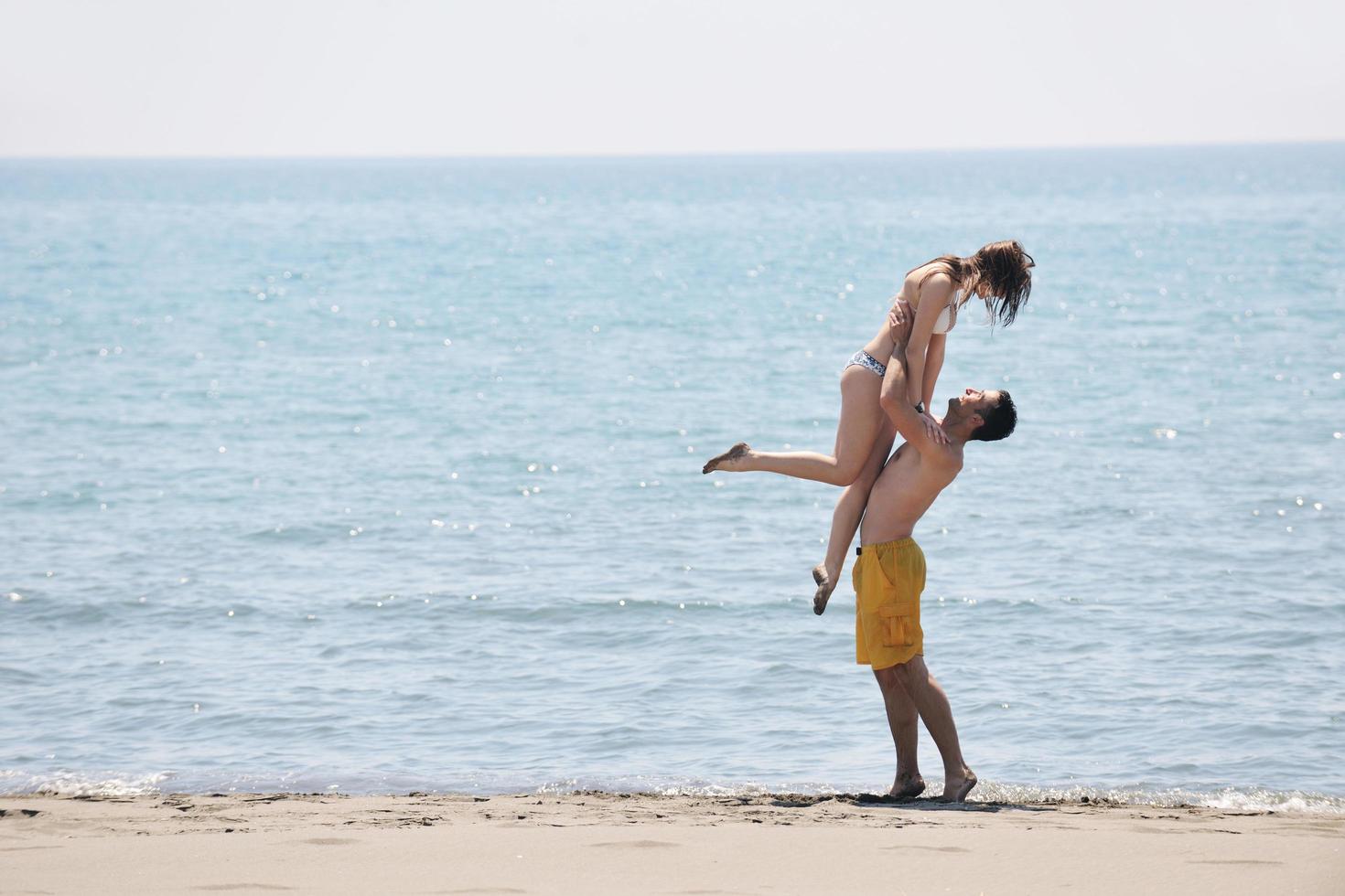 la giovane coppia felice si diverte sulla spiaggia foto