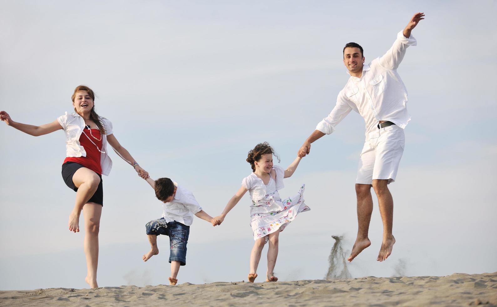 contento giovane famiglia avere divertimento su spiaggia foto