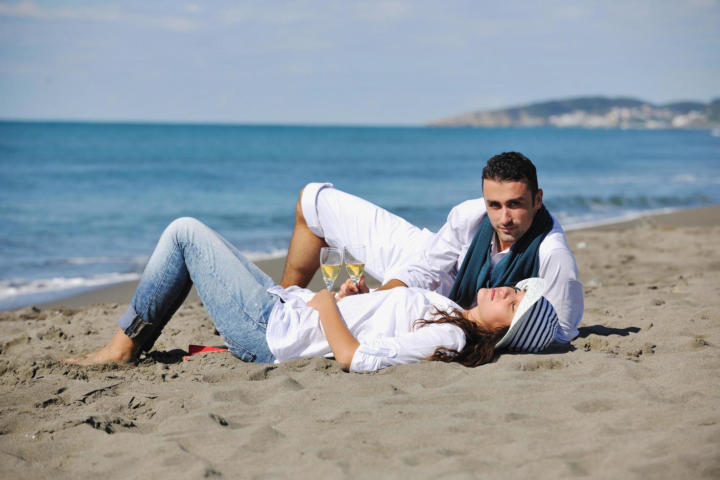giovane coppia godendo picnic su il spiaggia foto
