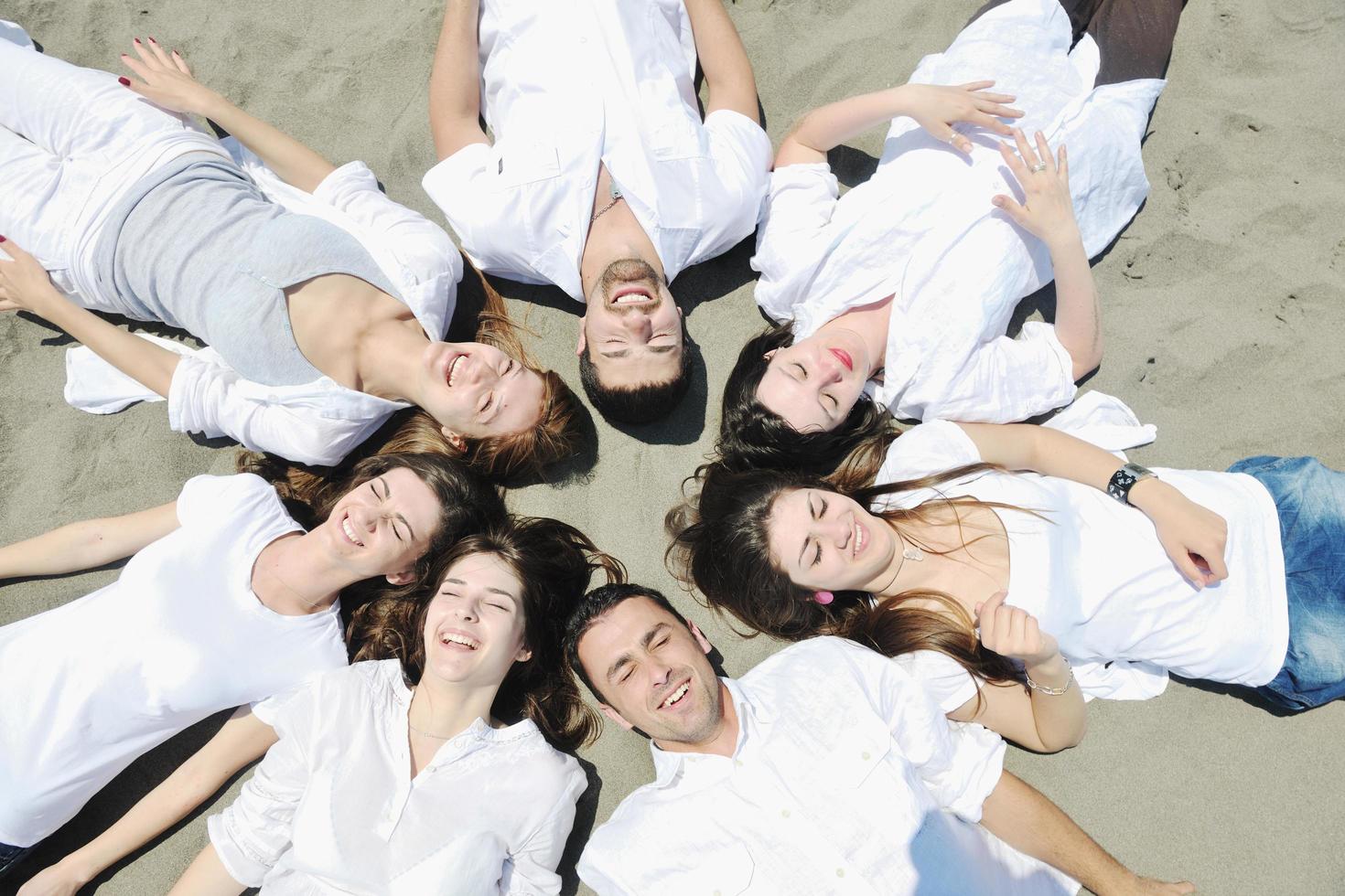 gruppo di contento giovane persone nel avere divertimento a spiaggia foto
