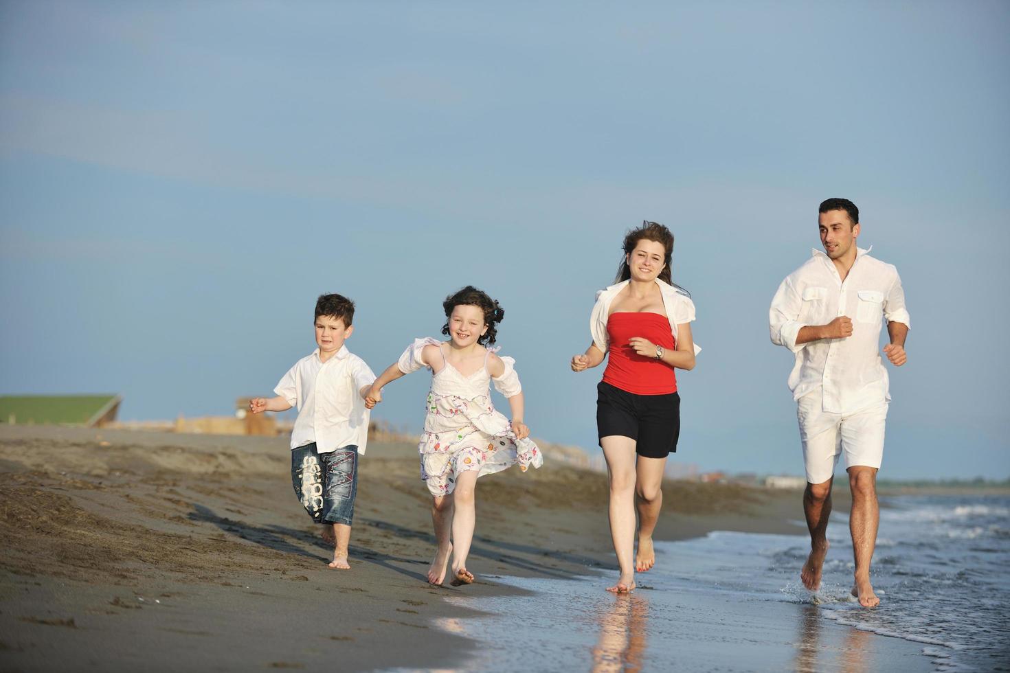 contento giovane famiglia avere divertimento su spiaggia foto