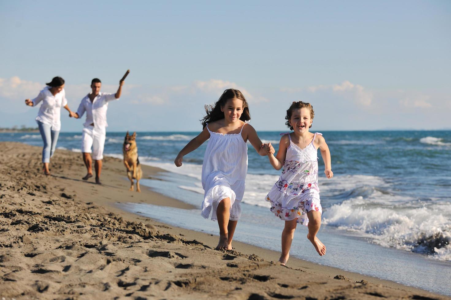 contento famiglia giocando con cane su spiaggia foto