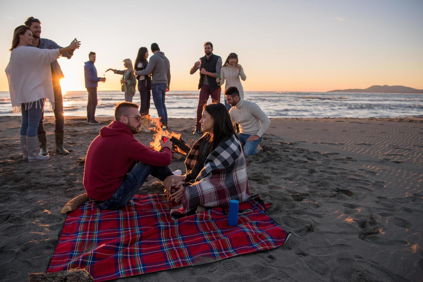 coppia godendo con amici a tramonto su il spiaggia foto
