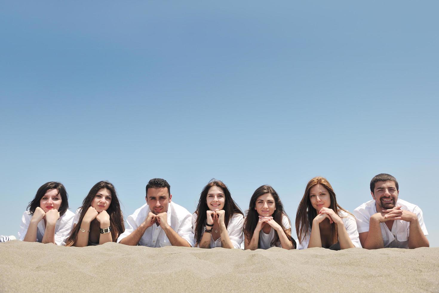 gruppo di contento giovane persone nel avere divertimento a spiaggia foto