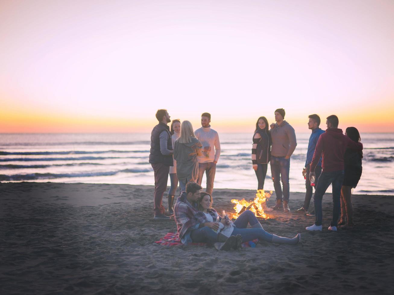 coppia godendo con amici a tramonto su il spiaggia foto