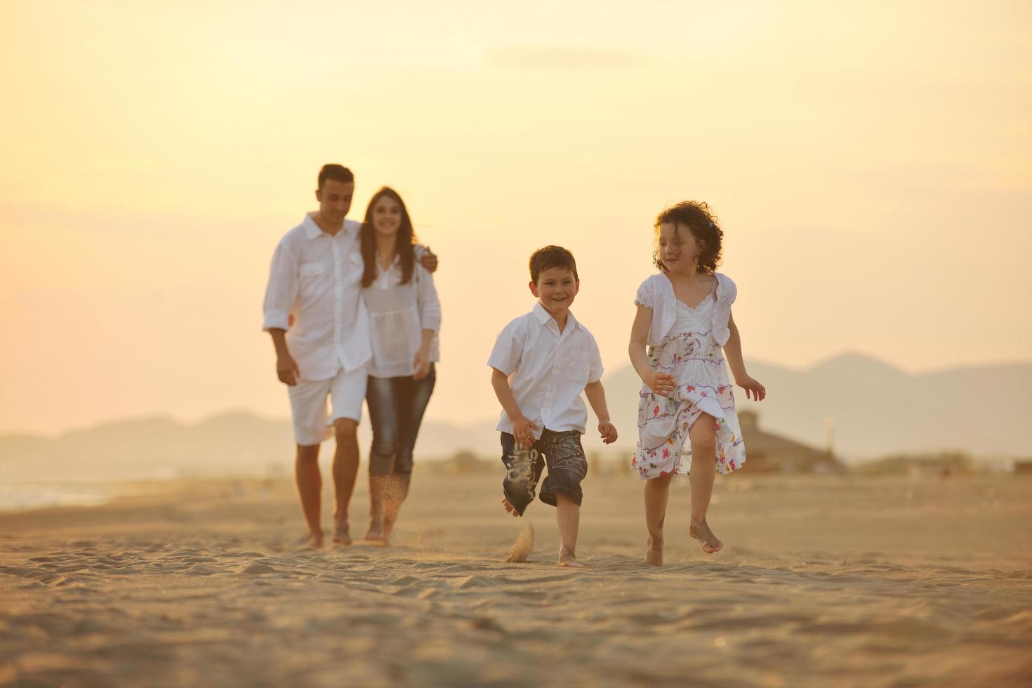 contento giovane famiglia avere divertimento su spiaggia a tramonto foto