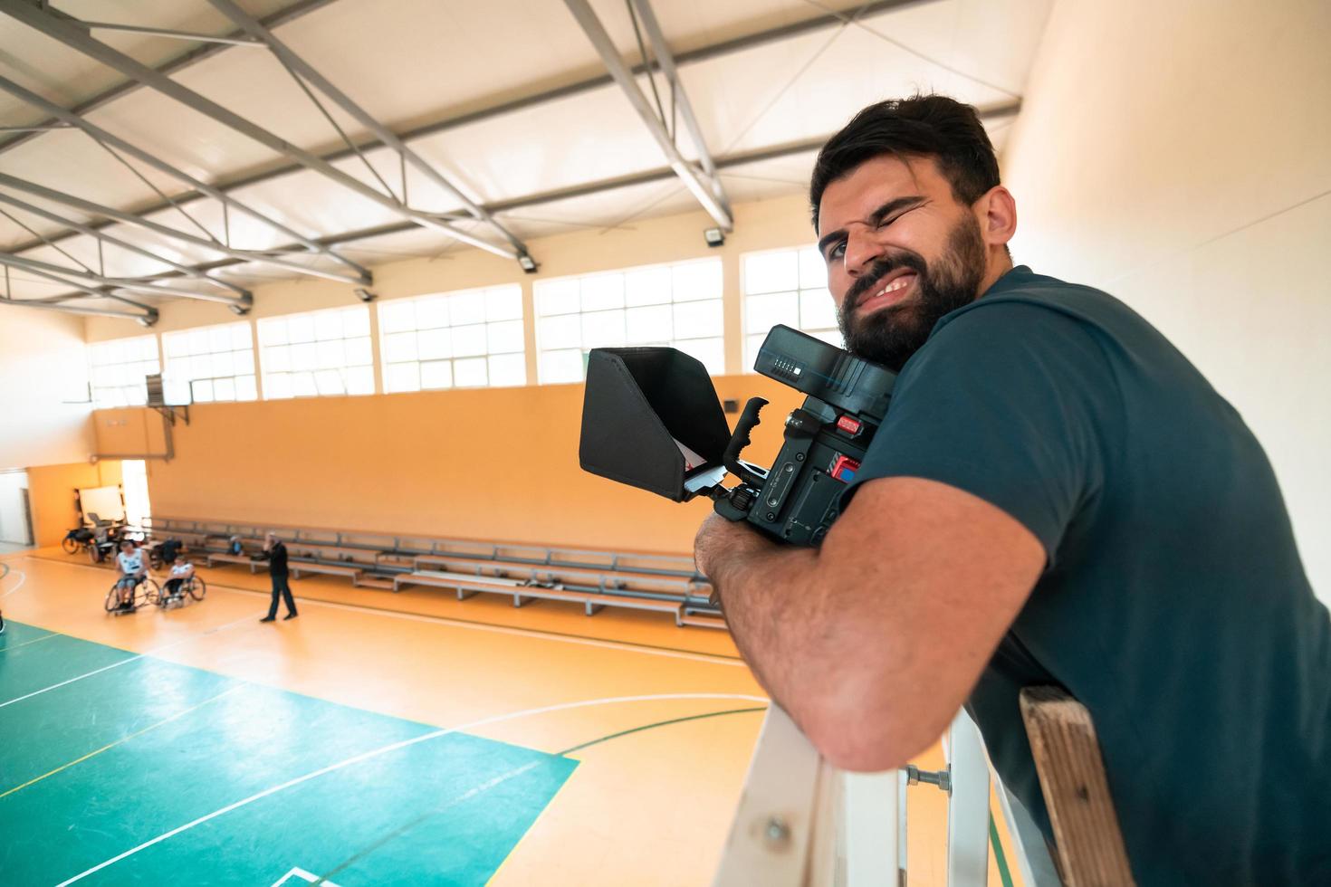un' cineoperatore con professionale attrezzatura record un' incontro di il nazionale squadra nel un' sedia a rotelle giocando un' incontro nel il arena foto