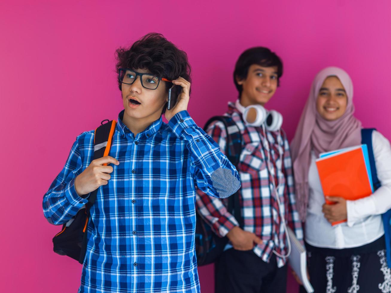 un' gruppo di arabo adolescenti, un' alunno squadra a piedi inoltrare in il futuro e indietro per scuola il concetto di un' rosa sfondo. il concetto di riuscito formazione scolastica per giovane le persone. selettivo messa a fuoco foto