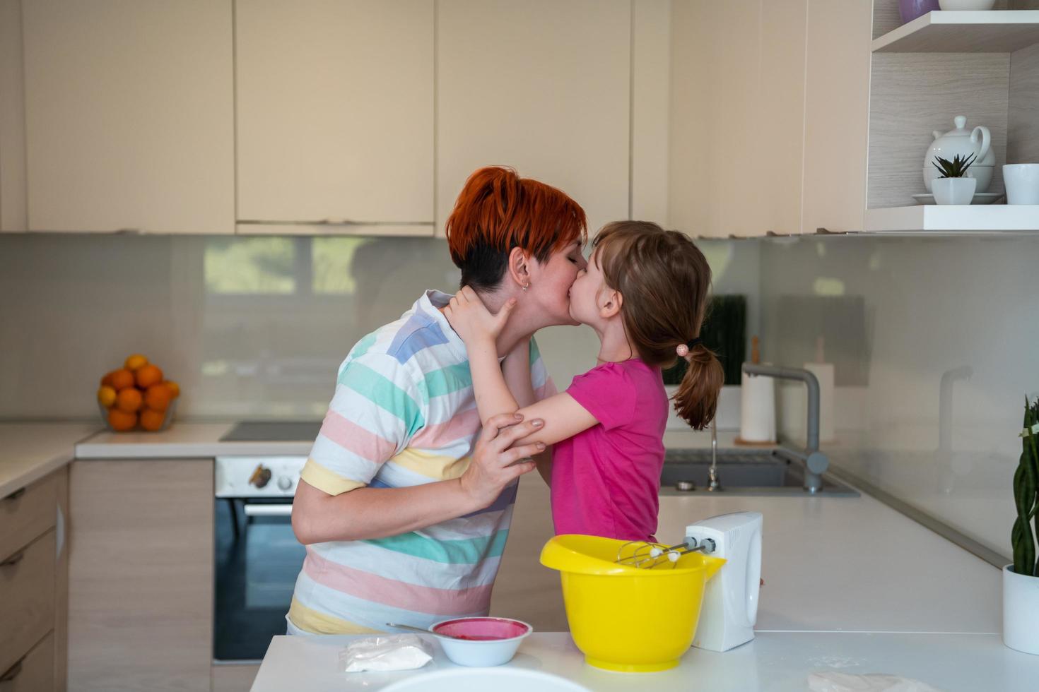 divertente poco ragazza aiutante giocando con Impasto su il suo mani apprendimento per impastare aiuta adulto mamma nel il cucina, contento carino bambino figlia e genitore mamma avere divertimento cucinando biscotti. foto