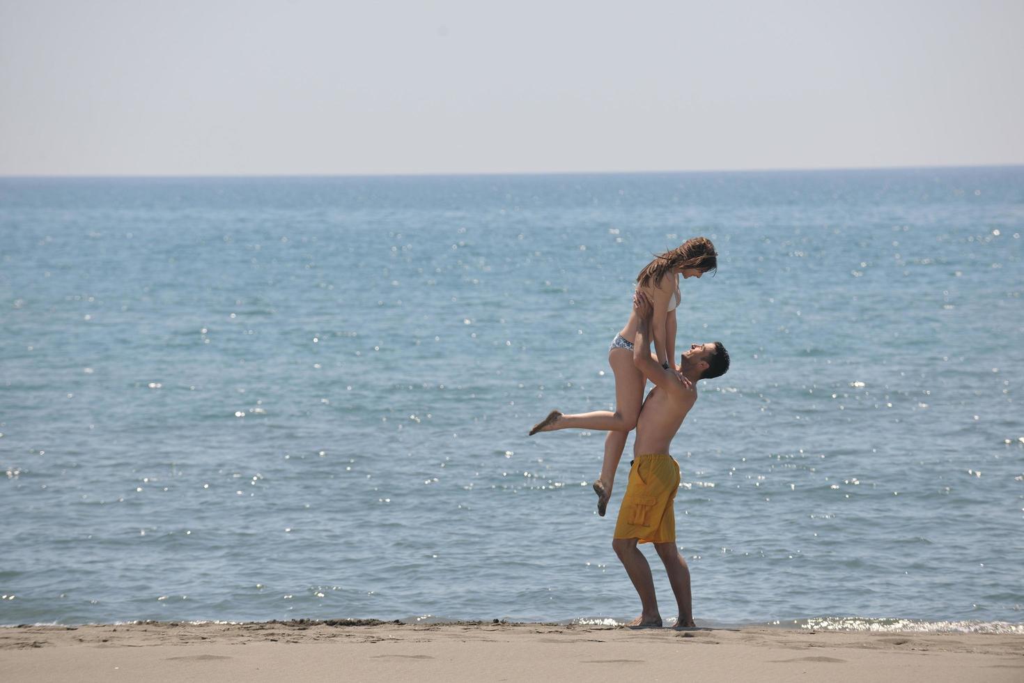 la giovane coppia felice si diverte sulla spiaggia foto