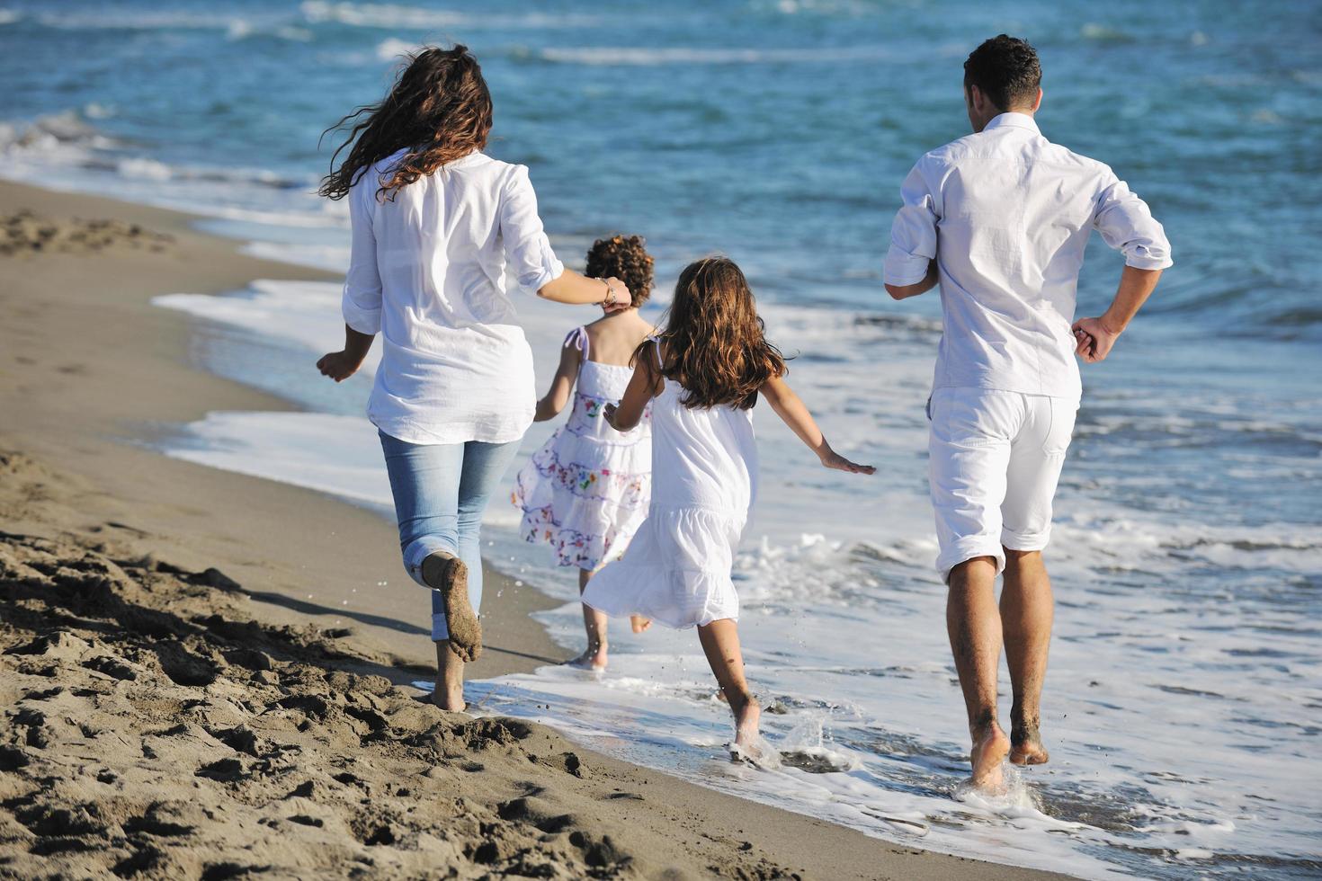 contento giovane famiglia avere divertimento su spiaggia foto