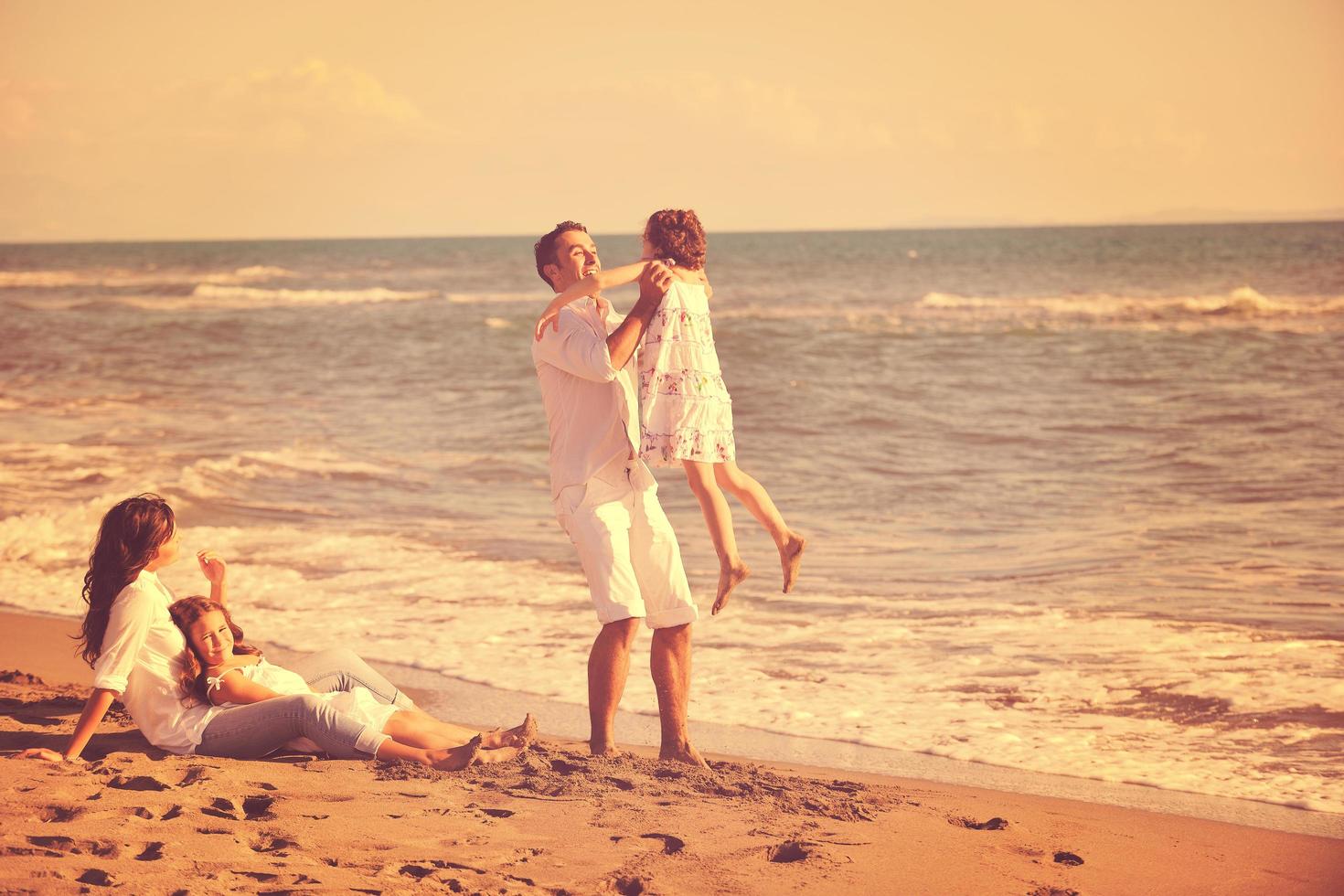 contento giovane famiglia avere divertimento su spiaggia foto