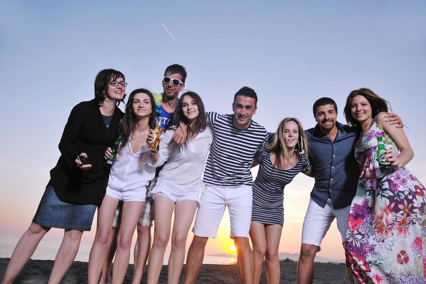 gruppo di giovane persone godere estate festa a il spiaggia foto