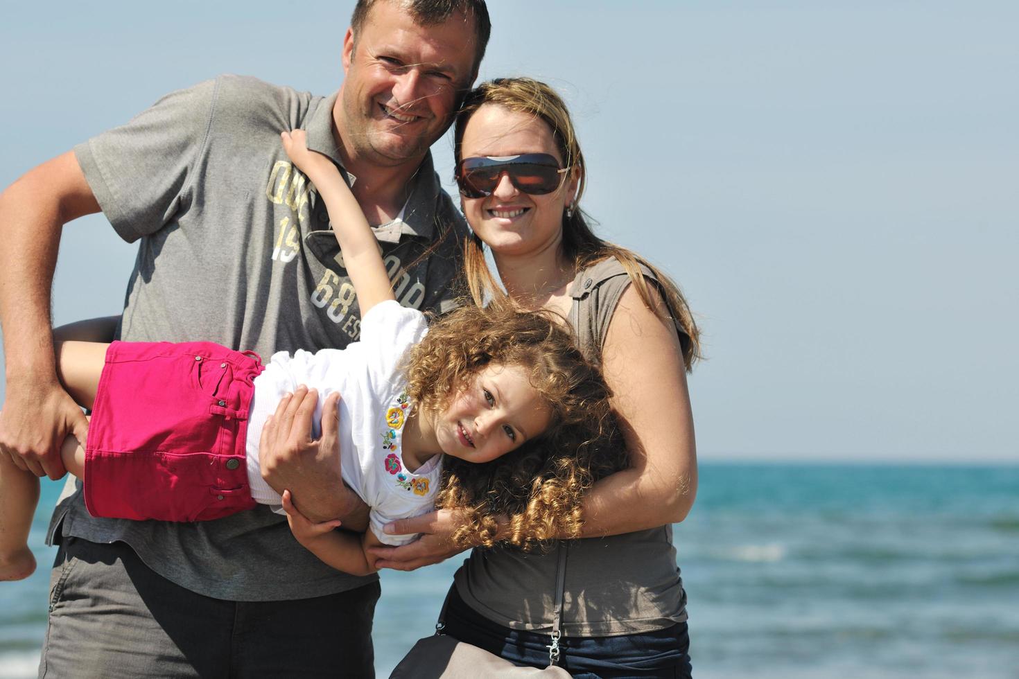 contento giovane famiglia avere divertimento su spiaggia foto