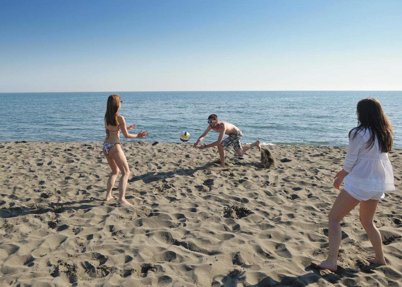 giovane persone gruppo avere divertimento e giocare spiaggia pallavolo foto