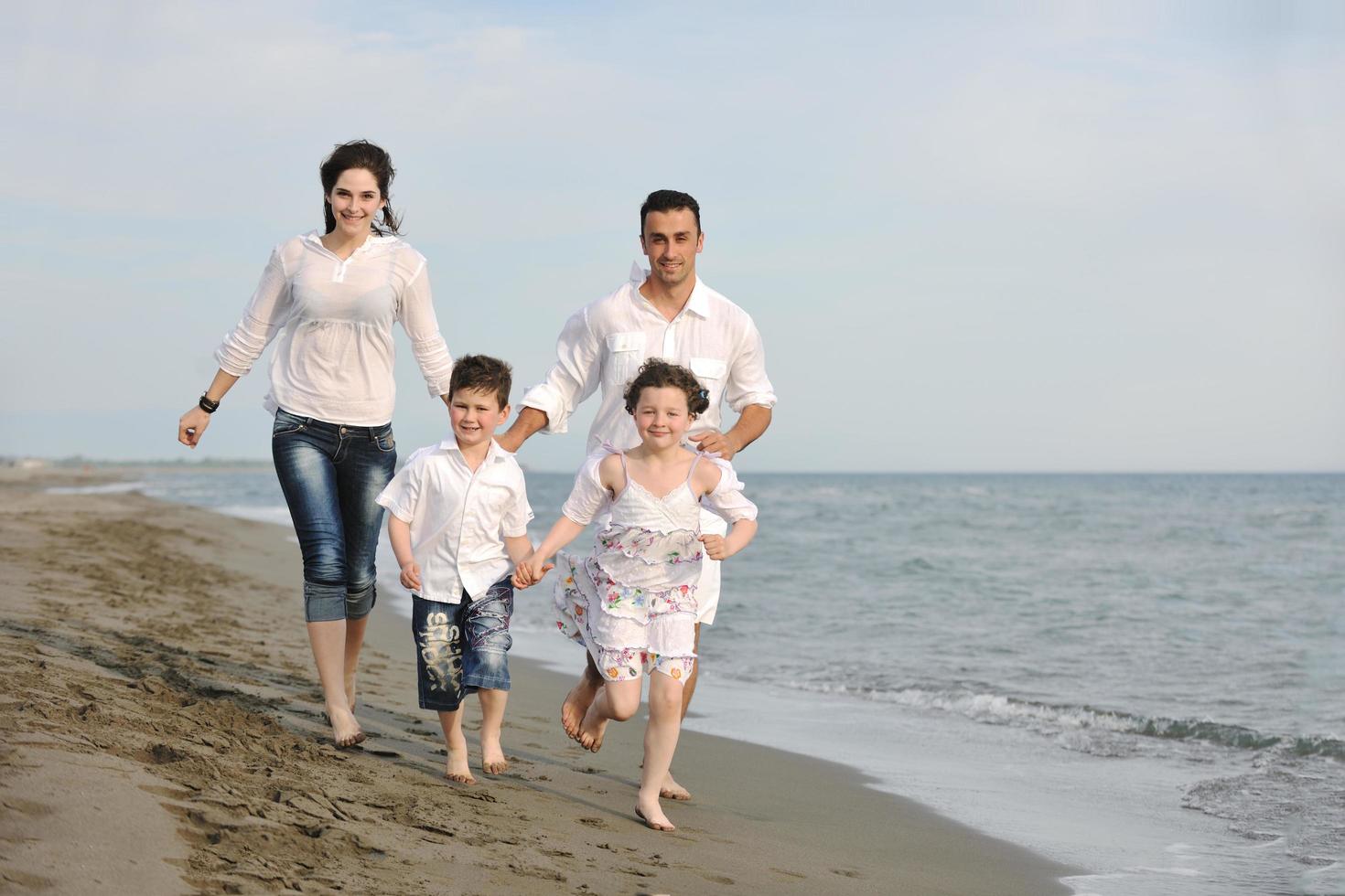 contento giovane famiglia avere divertimento su spiaggia foto